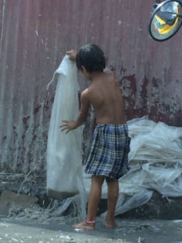 Filipijnen - Young boy is helping parents cleaning plastic