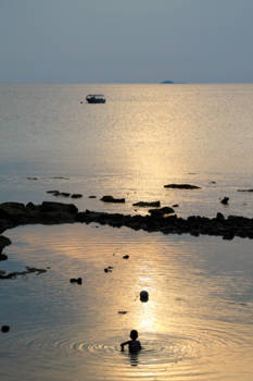 Maleisië - Jongetje speelt bij zonsondergang in Zuid-Chinese zee
