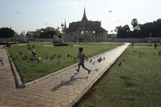 Phnom Penh - Vliegend en spelend kind in lijn met de vogels in Phnom Penh