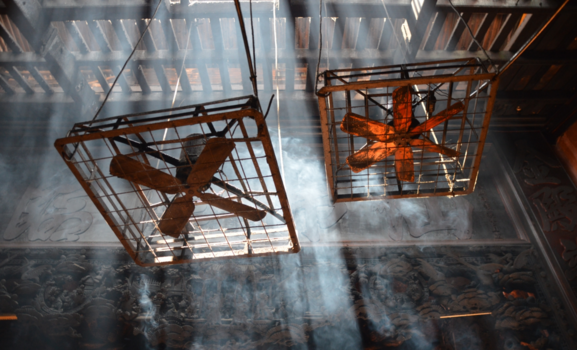 Ho Chi Minh Stad - Industrial fans, beautifully carved wood and a mist of incense in a temple in Saigon