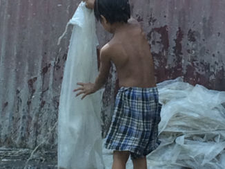 Filipijnen - Young boy is helping parents cleaning plastic